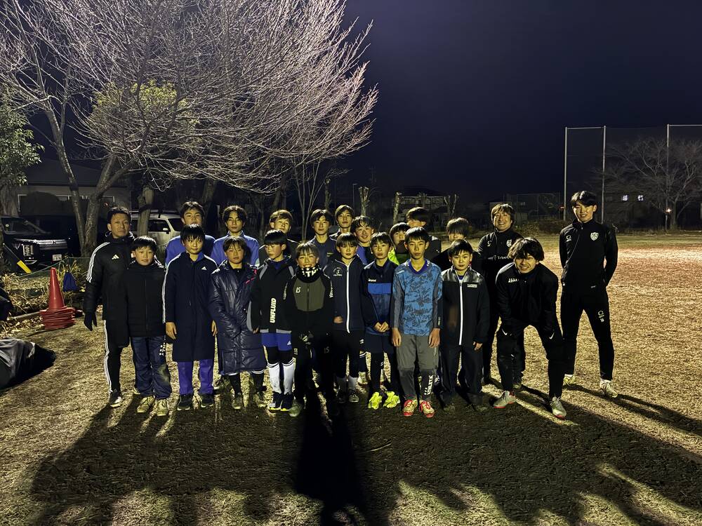 ナイター照明のグラウンドに並ぶF.C バイオレッツU-15スクールの中学生とコーチ