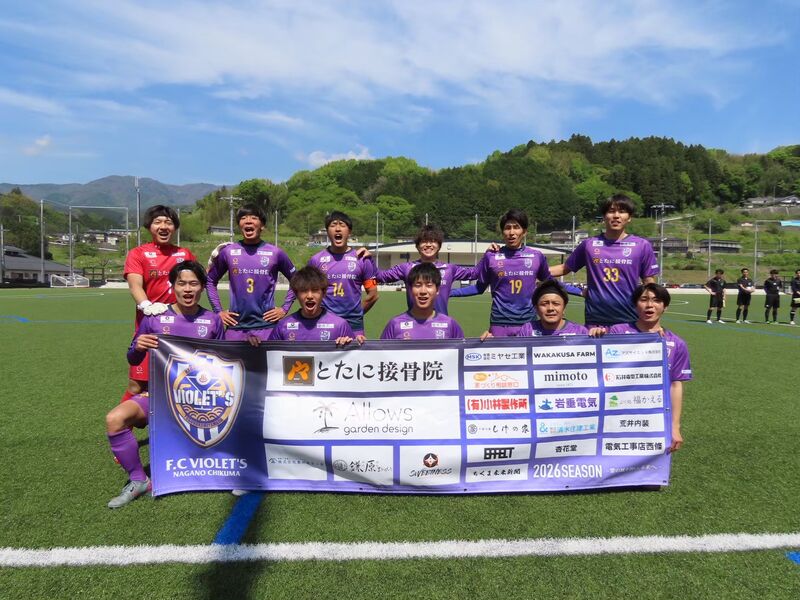 試合会場で、パートナー企業のロゴが並ぶ横断幕を選手たちが掲げている様子。